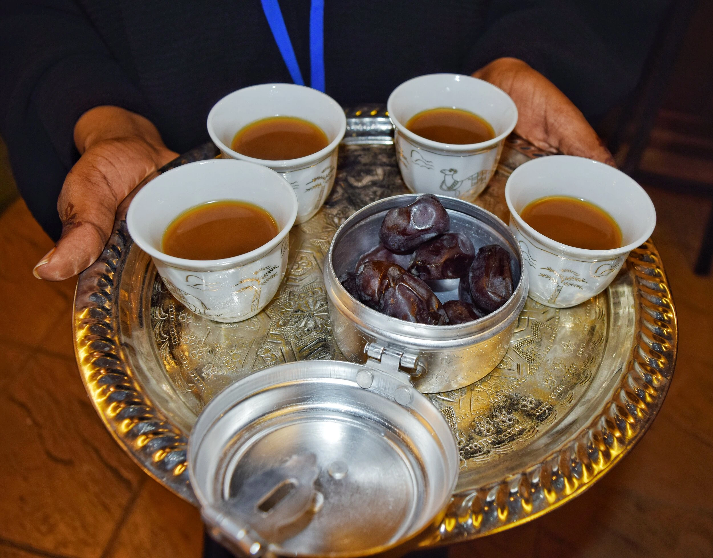Traditional Arabic coffee served in finjan cups with dates during a hospitality event in a women's majlis.