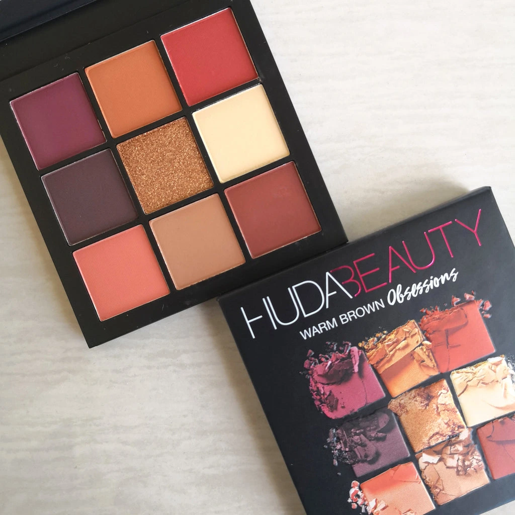 Huda Beauty eyeshadow palette featuring a variety of nude, pink, and brown shades in matte and shimmer finishes.
