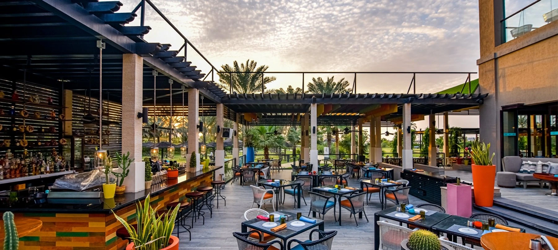Outdoor dining space at Maya Modern Mexican Kitchen with multicolor seating and overgrown garden views.