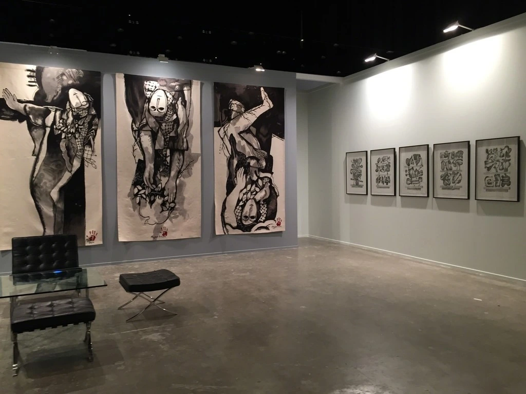 A beautiful black artwork on a white canvas is displayed against grey walls at Meem Gallery.
