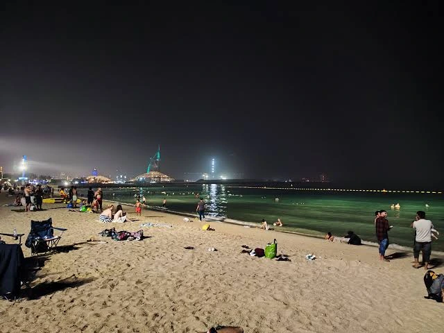 Night view of JBR Beach Dubai with cozy wooden beach beds and large umbrella rentals.