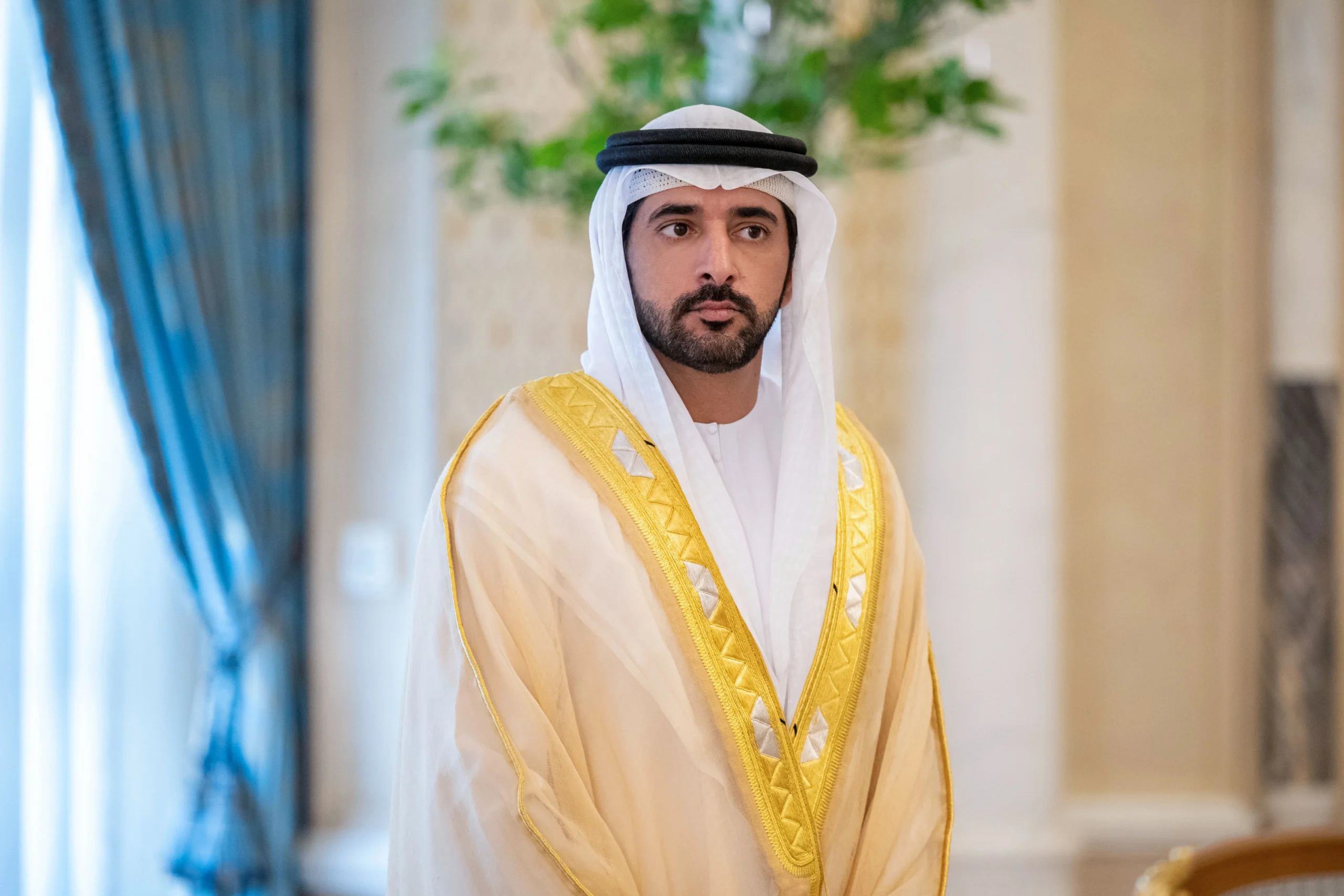 Sheikh Hamdan bin Mohammed is in a golden-trimmed traditional Emirati robe.