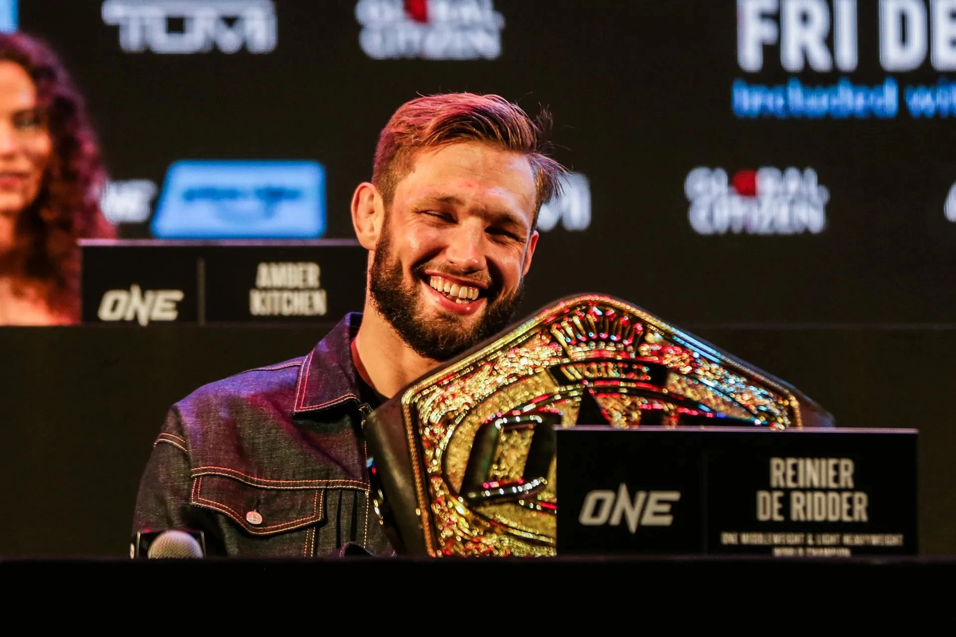 Reinier de Ridder smiling while holding his ONE Championship belt, posing for a pic.