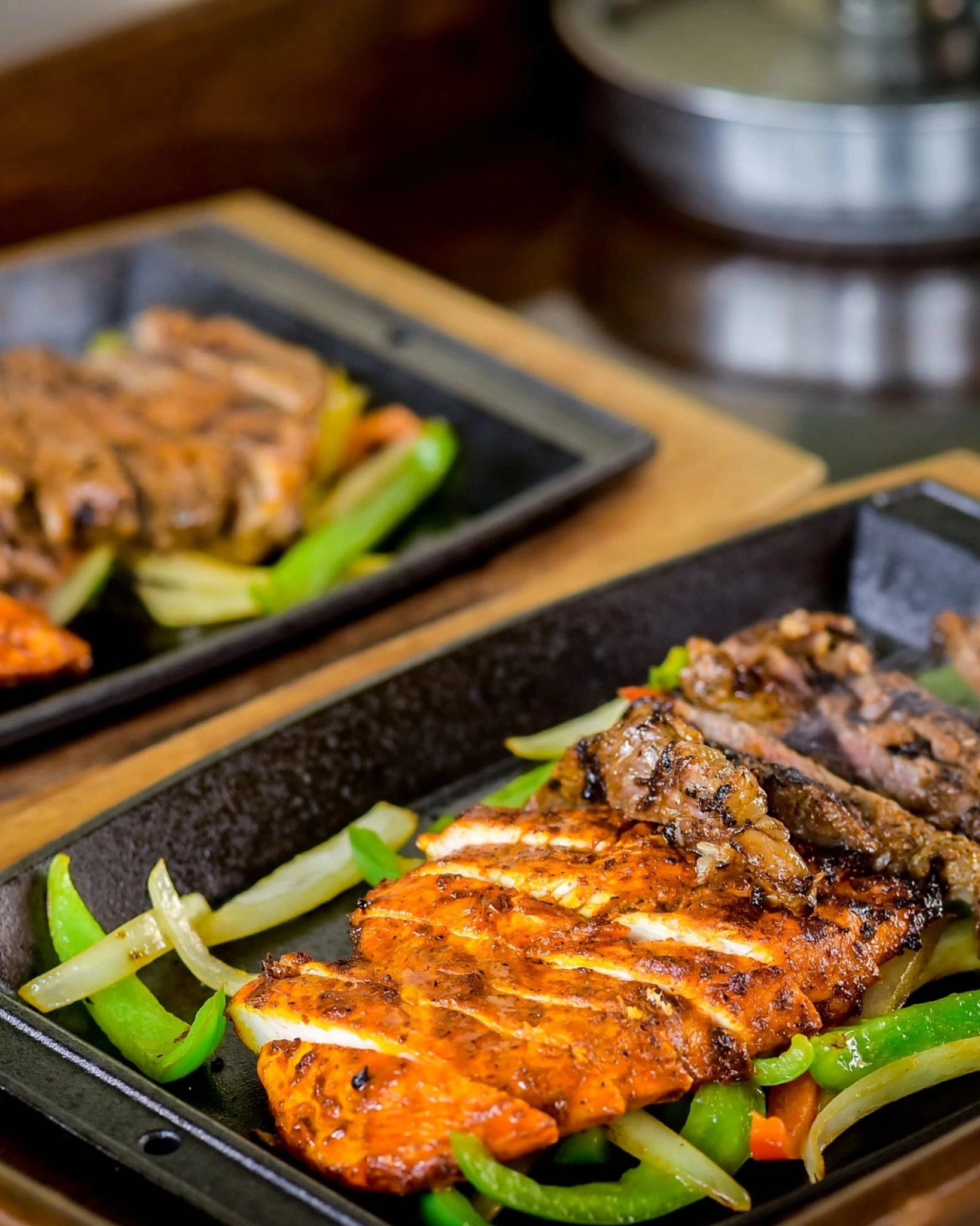 Sizzling chicken and beef fajitas on a sizzling skillet with grilled peppers and onions.