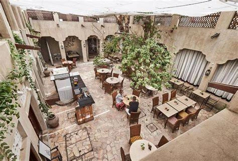 The open courtyard of XVA Gallery showcases art pieces displayed on rustic walls and floor, creating a warm, cultural atmosphere.